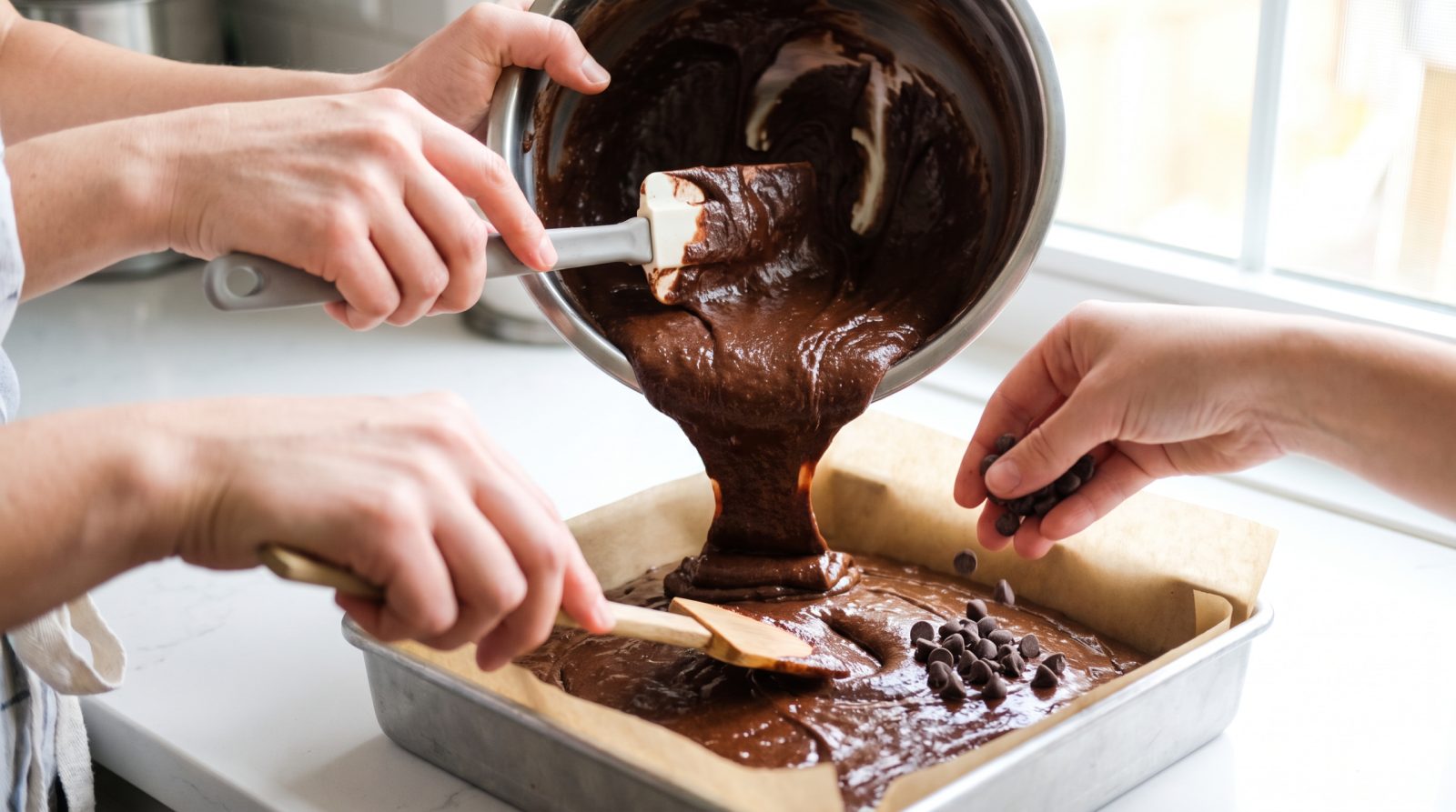 Glossy brownie batter poured into a parchment-lined pan topped with chocolate chips